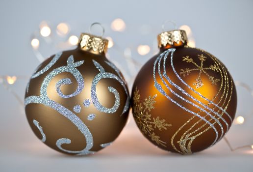 Two gold Christmas decorations with decorative lights on gray background