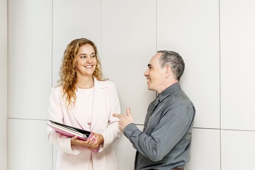 Man and woman discussing work in business office hallway