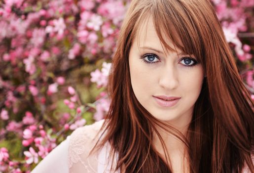 Beautiful girl posing over spring flowers background