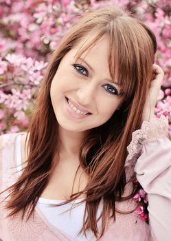 Beautiful girl posing over spring flowers background