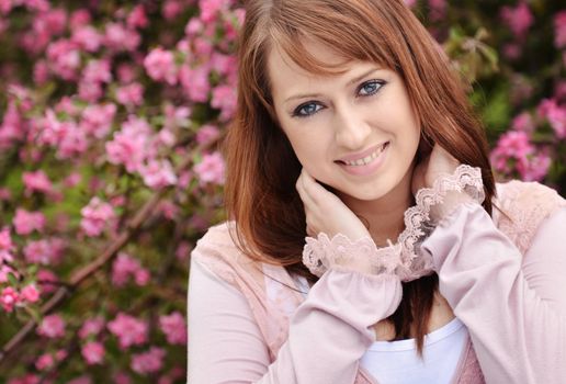 Beautiful girl posing over spring flowers background