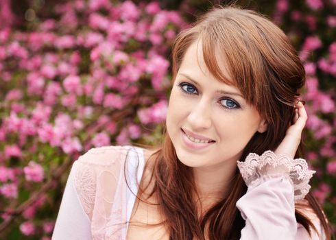 Beautiful girl posing over spring flowers background