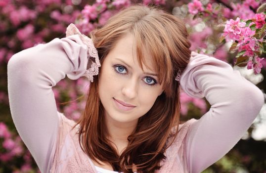 Beautiful girl posing over spring flowers background