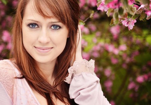 Beautiful girl posing over spring flowers background