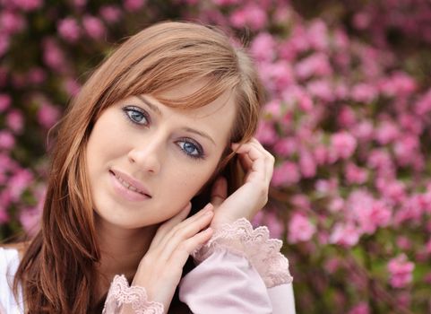 Beautiful girl posing over spring flowers background