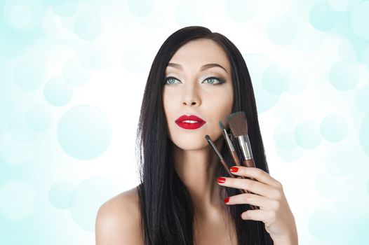 beautiful woman with brushes for makeup on the background bokeh