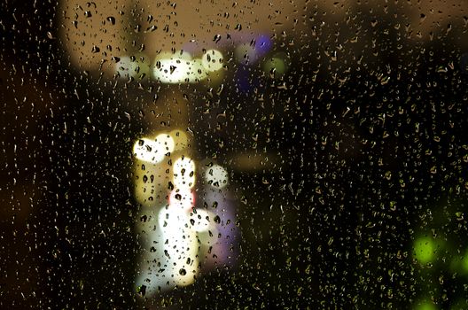 view of the city lights through rainy window