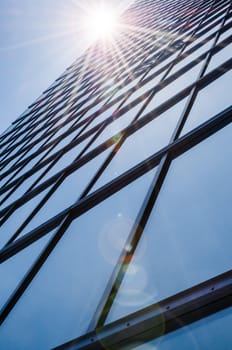 Steel and glass - mirrored facade of modern skyscraper with glare reflection