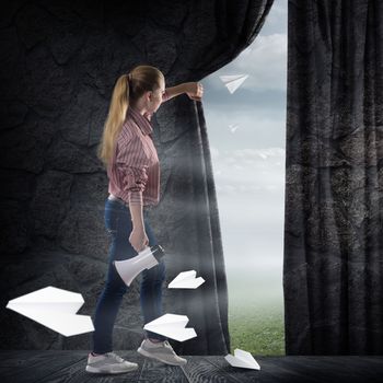image of a young woman pushes the curtain looking at flying paper airplanes