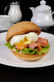 Appetizing bun with sesame seeds and thin slices of salmon and poached egg
