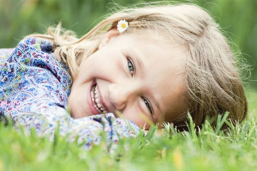 Little adorable girl lying on grass laughing