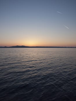 Island coast at sunrise with sky with plane traces