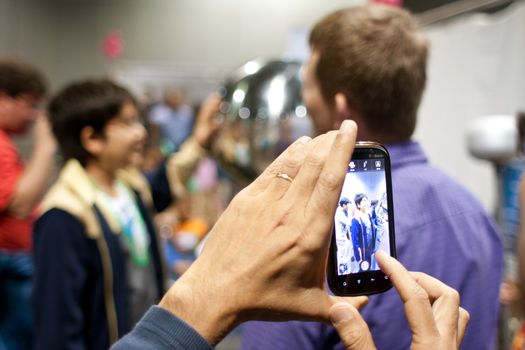 Atlanta, GA, USA -  March 29, 2014:  Closeup of man's hands using camera phone to take picture of his son at the Atlanta Science Expo.  The event was free and open to the public. 