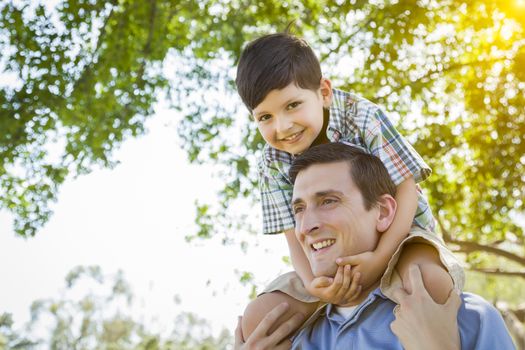 Mixed Race Father and Son Playing Piggyback Together in the Park.