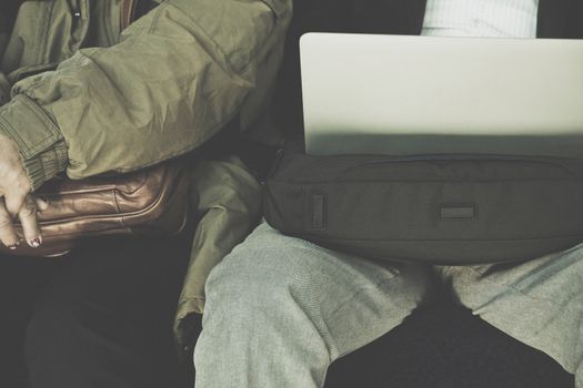 Businessman sitting on seat of train and playing Laptop