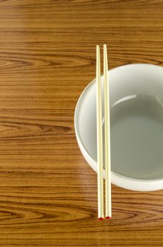empty white bowl with chopstick on wood table background