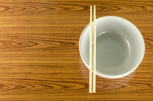 empty white bowl with chopstick on wood table background
