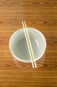 empty white bowl with chopstick on wood table background