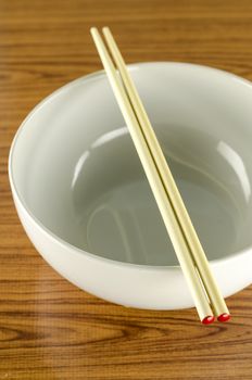 empty white bowl with chopstick on wood table background