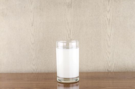 milk in a glass on wood background