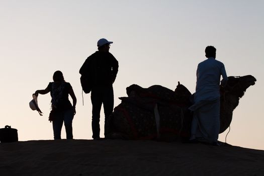 This couple getting ready to mount the camel for their safari into the Thar Desert near Jaisalmer in Rajasthan , India, stand out against the sky of the evening light and make for a graphic composition.