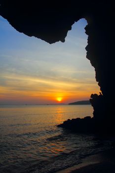 View on beautiful sunset above the sea through rock silhouette