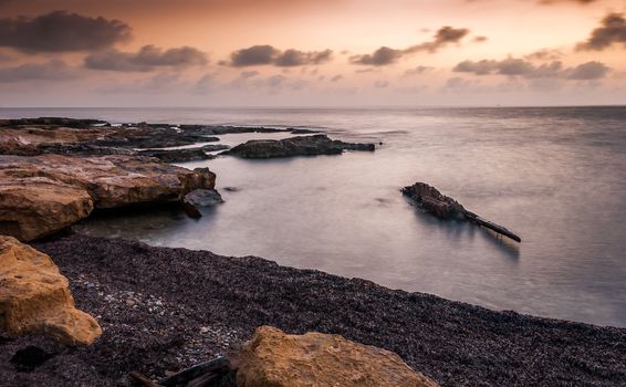 rocky beach with shipwreck on cloudy morgning