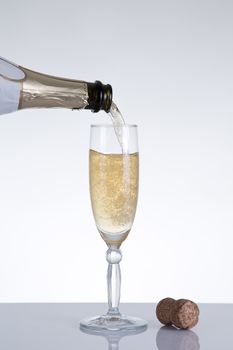 Champagne pouring into an elegant glass, studio shot on grey background 