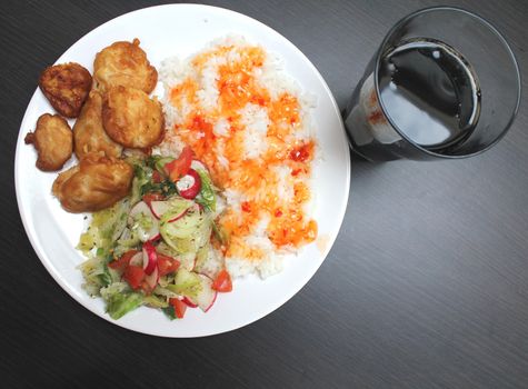 chicken on a plate with rice and salad, shot from above