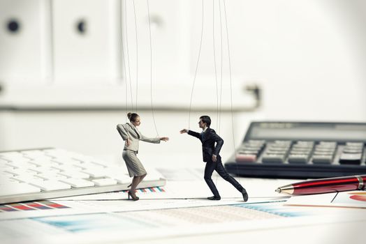 business man and lady dolls puppets on the desk, next to the documents and stationery items