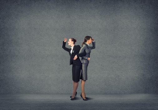 two business women holding hands, looking in different directions, teamwork