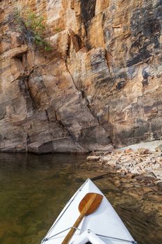 canoe bow with a paddle on Horsetooth Reservoir with a high sandstone cliff, Fort Collins, Colorado