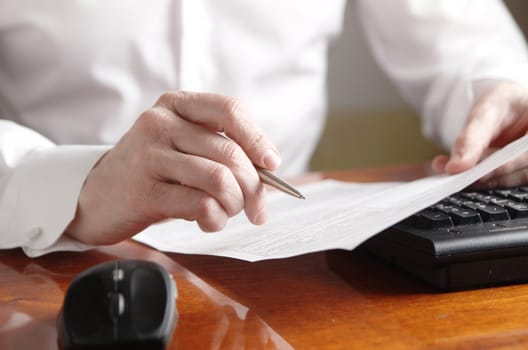 Hands with a document and a pen on a computer keyboard