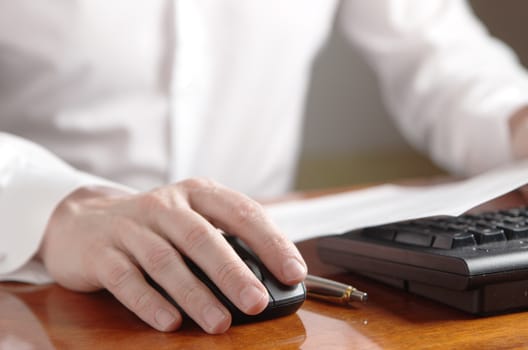 Men's hand on computer mouse next to the keyboard