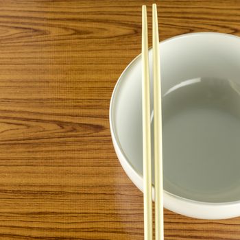 empty white bowl with chopstick on wood table background