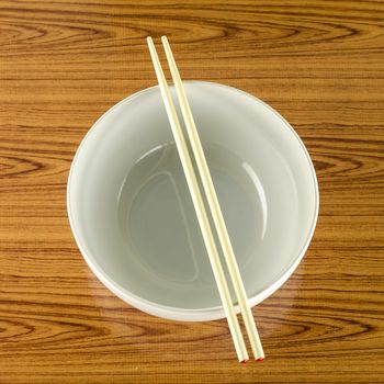 empty white bowl with chopstick on wood table background