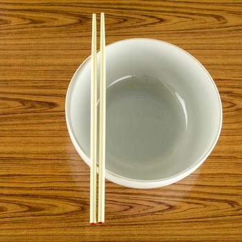 empty white bowl with chopstick on wood table background