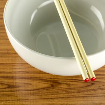 empty white bowl with chopstick on wood table background