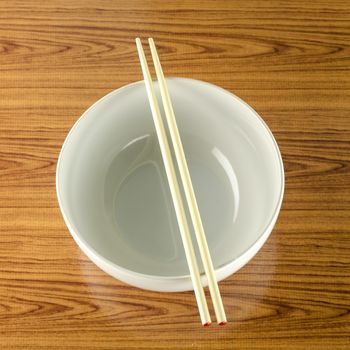 empty white bowl with chopstick on wood table background