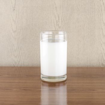 milk in a glass on wood background