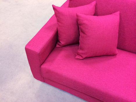 Bright modern pink sofa with two cushions.
