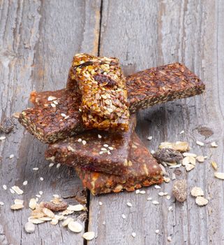 Stack of Useful Granola Bars with Muesli, Nuts, Seed and Raisins closeup on Rustic Wooden background