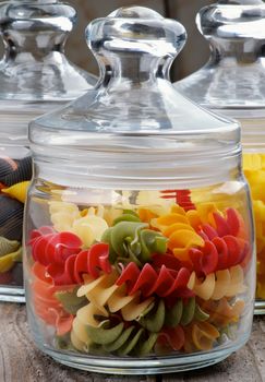 Colorful Raw Pasta in Glass Jars closeup Wooden background