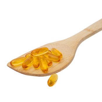 wood spoon full of fish oil capsules