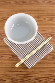 white bowl and chopstick with kitchen towel on wood background