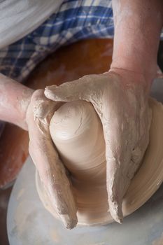 Hands of a potter, creating an earthen jar on the circle