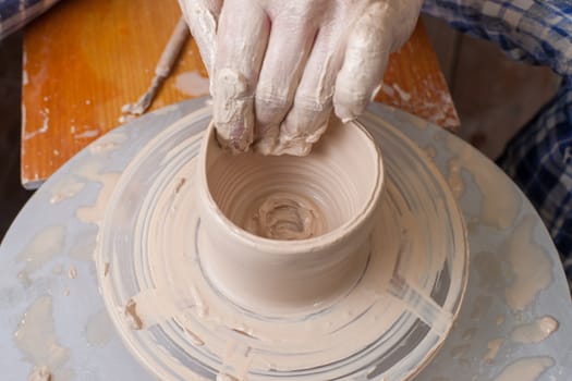 Hands of a potter, creating an earthen jar on the circle