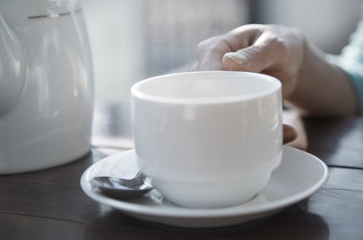 Woman hand holding teacup at outdoors cafe
