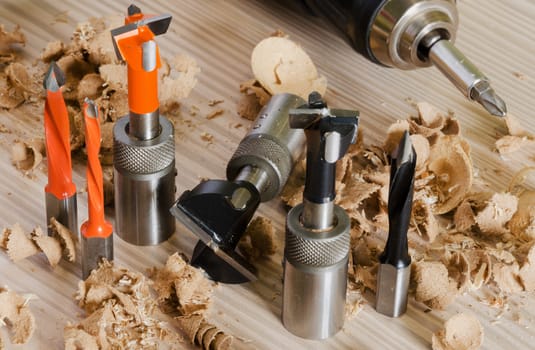 Machine tool cutters and drill bits in the sawdust on wood background