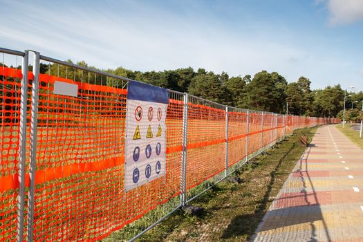 A orange fence with warning signs on it